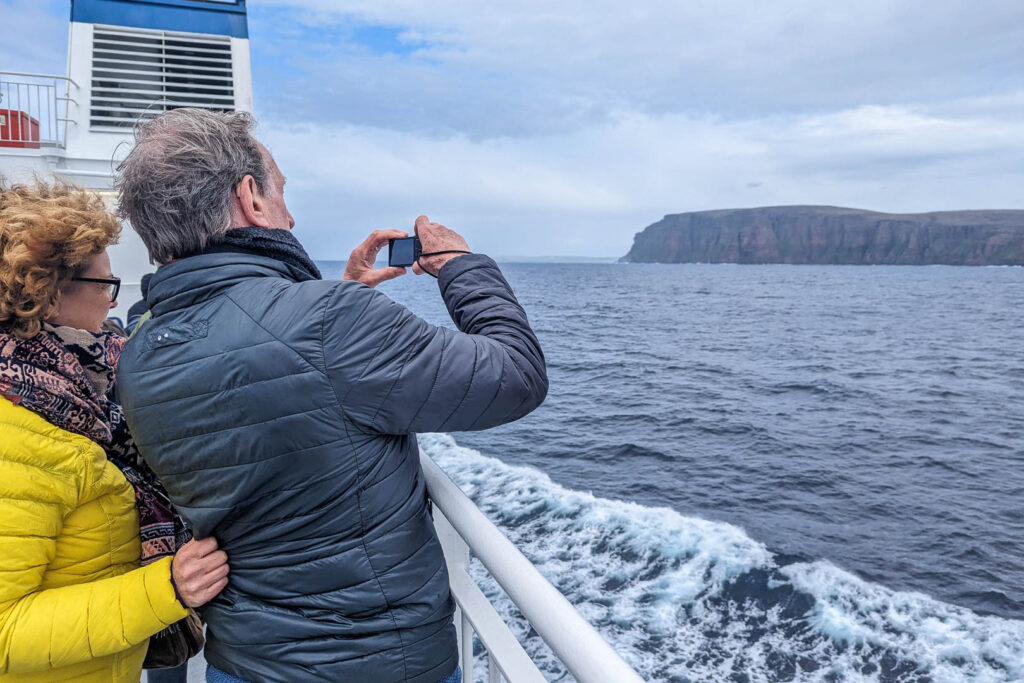 A couple taking photos of Hoy aboard the Ferry to Orkney