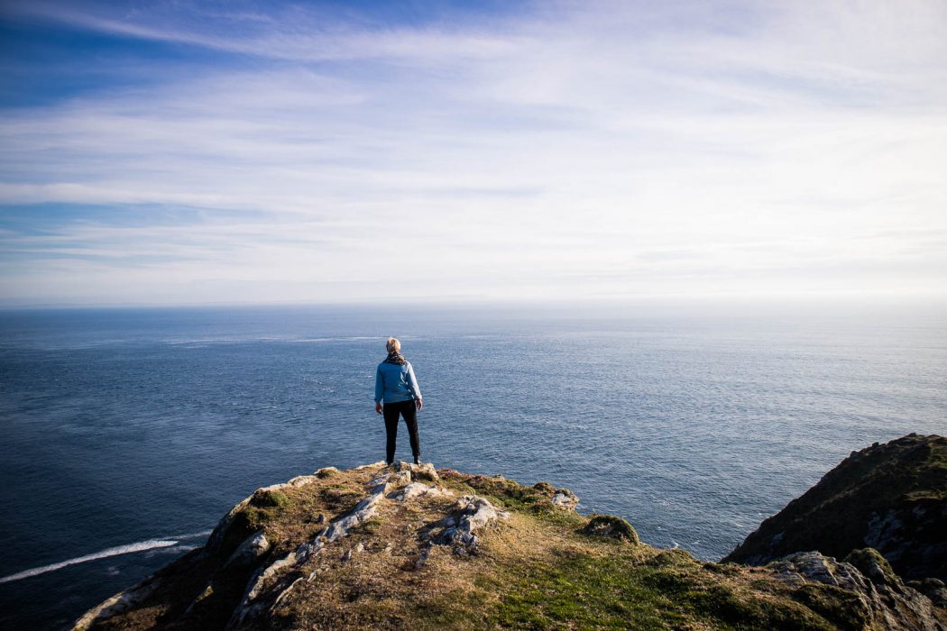 A woman standing on a cliff overlooking the ocean