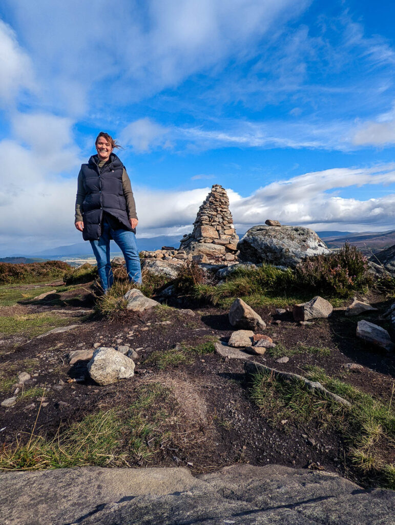 kathi standing at a summit cairn in badenoch