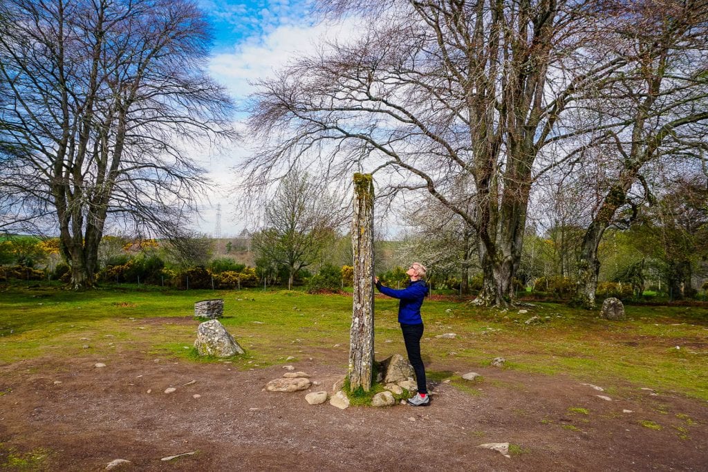 A woman standing in front of a standing stone in Scotland