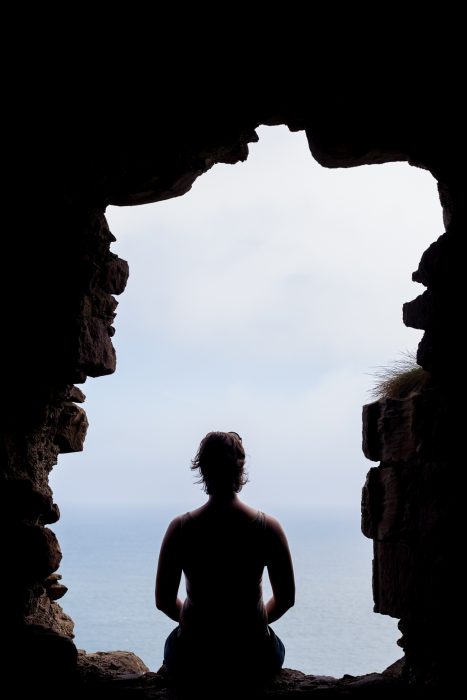A woman sitting in a stone window at Dunnottar Castle in Scotland