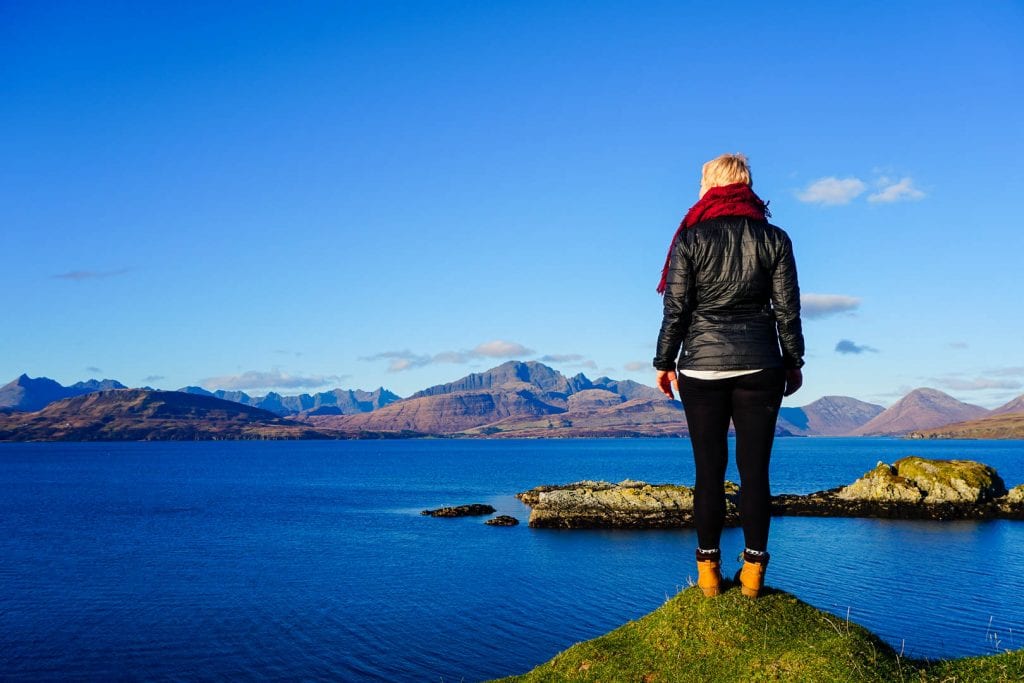 A woman standing at the Sleat Peninsula on Skye looking at the sea and mountains.