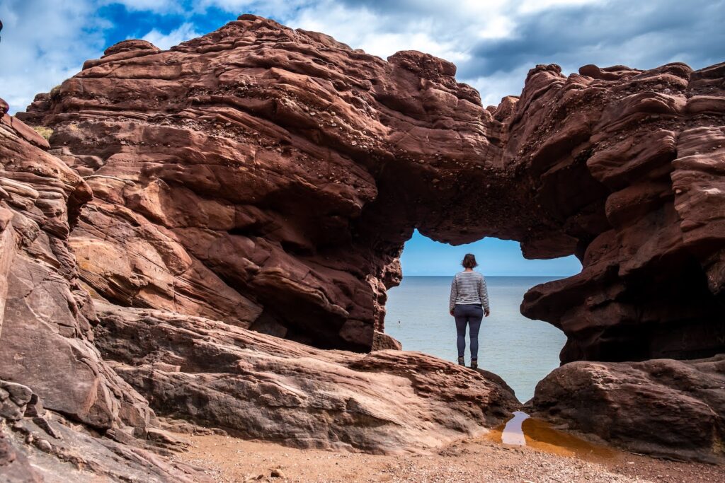 a woman standing in a stone arch at the Seaton Cliffs in Arbroath