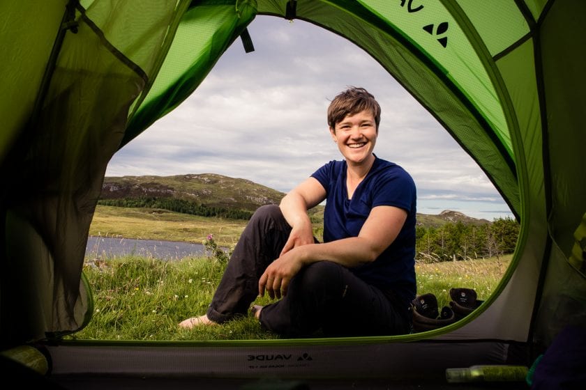 Travel writer and hiker Kathi Kamleitner outside her tent while wild camping in Scotland.