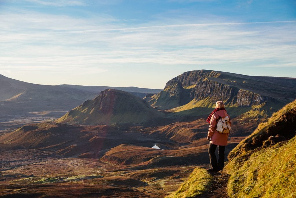 Woman standing in the hills of Scotland at sunrise.
