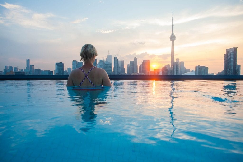 Girl watches sunrise from infinity pool on Thompson Toronto hotel in Toronto.